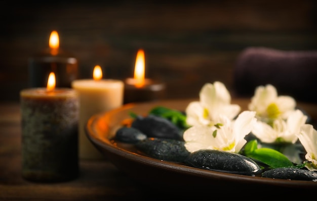 Foto bol de madera de spa con flores de agua y piedras sobre fondo de madera