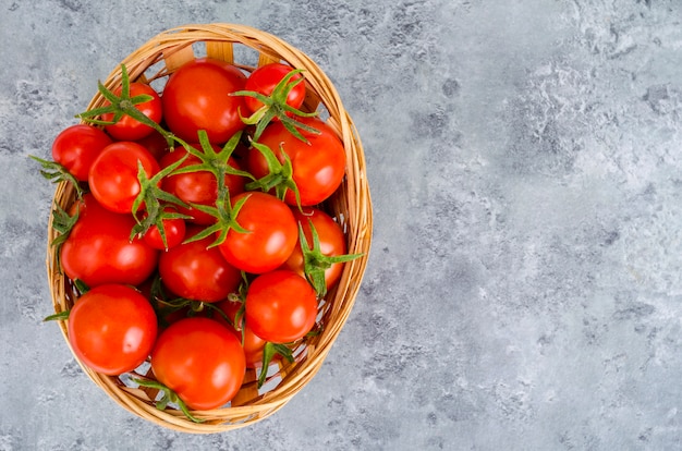 Bol de mimbre con tomates rojos. Foto de estudio