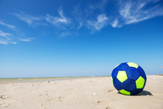 Foto bola azul na areia na praia contra o céu