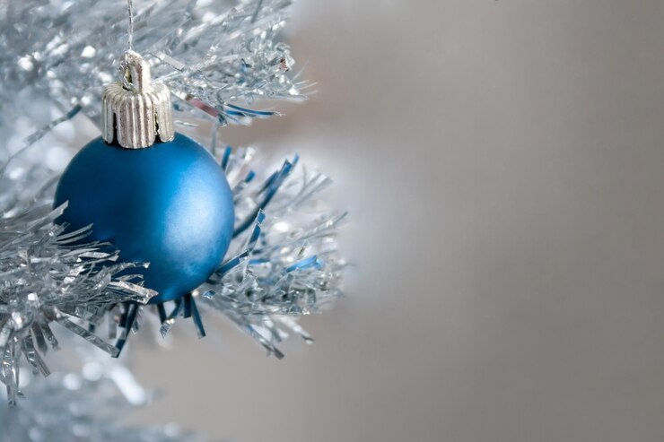 Bola azul sobre un árbol de Navidad artificial plateado con espacio de copia