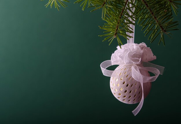 Bola branca pendurada em um galho de árvore de Natal no verde