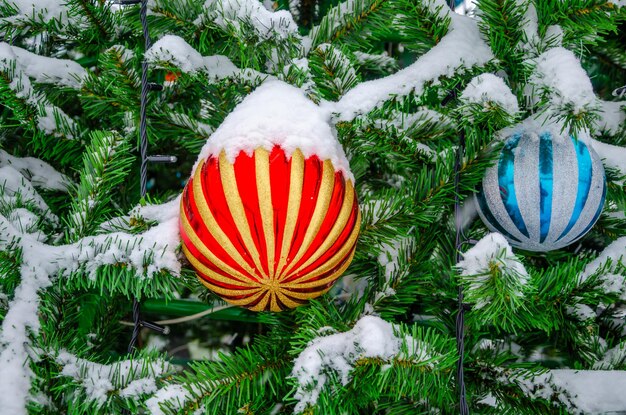 Una bola de cristal en un árbol de Navidad bajo la nieve.