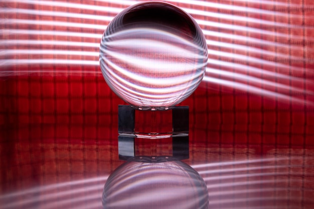 Bola de cristal que refleja un fondo rojo con luces a su alrededor, pintura de luz, enfoque selectivo.