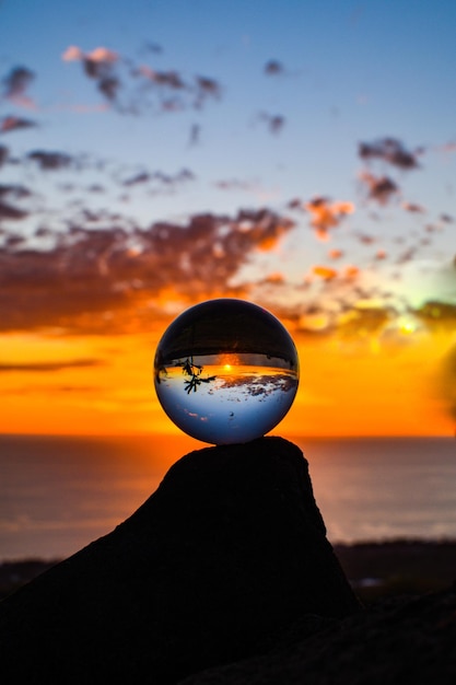 Foto bola de cristal con el reflejo del mar y el cielo nublado durante la puesta de sol