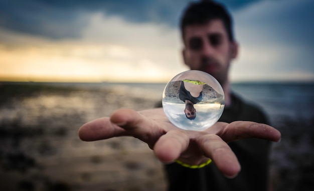 Foto bola de cristal sobre la mano en la playa.