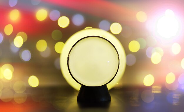 Bola de cristal sobre la mesa con bokeh, luces detrás. Bola de cristal con luz colorida bokeh, concepto de predicción.