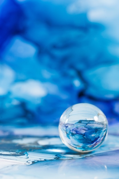 Una bola de cristal transparente sobre un fondo azul abstracto la técnica de la tinta alcohólica