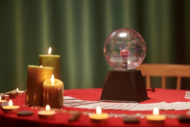 Bola de cristal y velas encendidas en la mesa del vidente