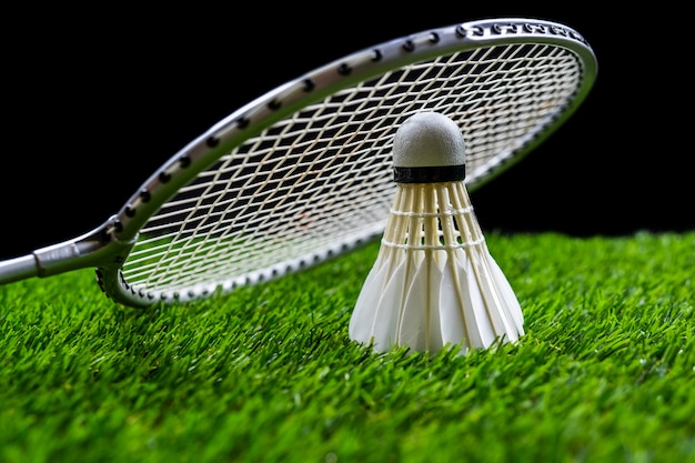 Bola de badminton e raquete na grama em fundo preto