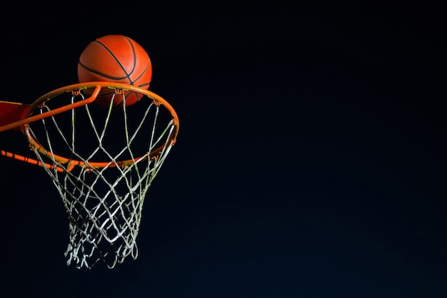 Bola de basquete de rua caindo na cesta à noite, jogo da juventude urbana.