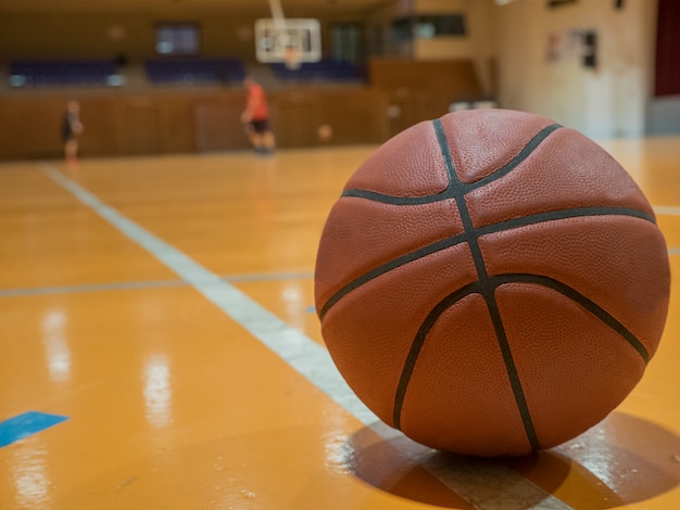 Bola de basquete na quadra com linha de lance livre, jogadores fora de foco