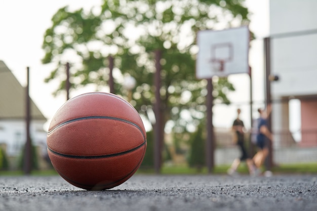 Bola de basquete na quadra de rua ao ar livre jogadores joga um jogo no fundo