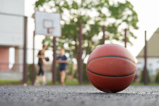 Bola de basquete na quadra de rua ao ar livre jogadores joga um jogo no fundo