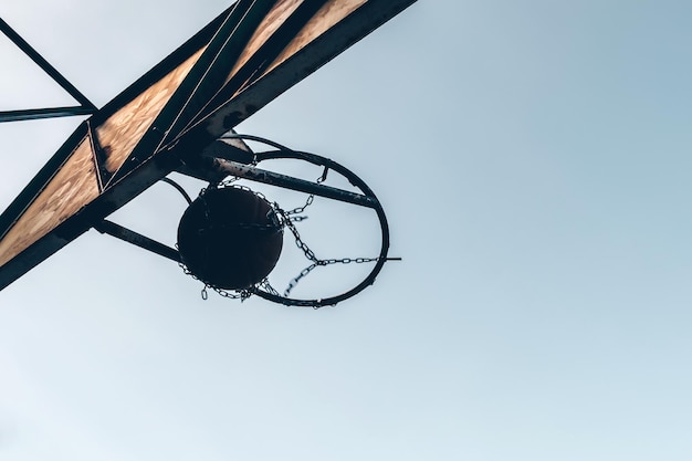 Bola de basquete passando pelo aro ao ar livre contra o pano de fundo do céu Conceito esportivo