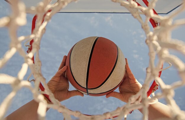 Bola de basquete voando pela cesta no esporte de mãos de jogadores