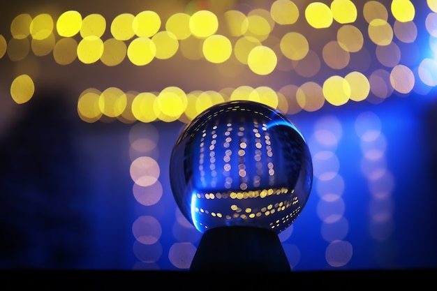 Bola de cristal no chão com bokeh, luzes atrás. Bola de vidro com luz colorida do bokeh, conceito de celebração do ano novo.
