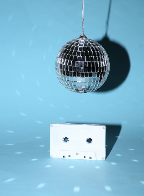 Bola de discoteca com cassete de áudio retrô em fundo azul brilhante conceito de festa minimalista