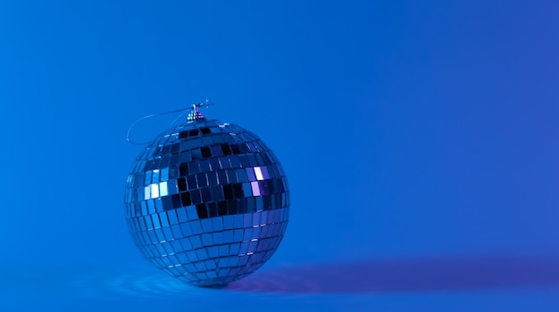 Bola de discoteca em um fundo azul desfocado o conceito de dançar música disco e festas copiam o espaço