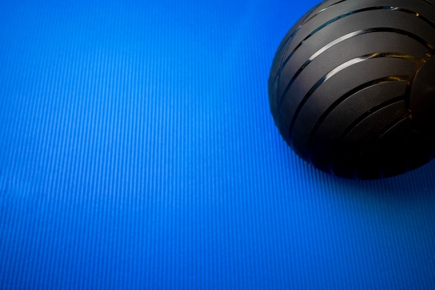 Foto bola de fitness preta no tapete azul backgorund