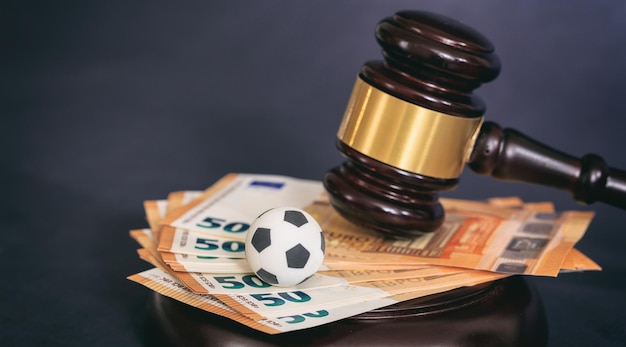 Bola de futebol e euros do martelo da lei no fundo preto