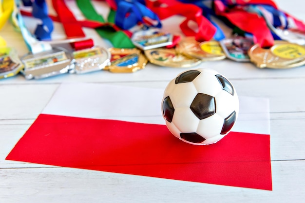 Bola de futebol e medalhas de bandeira polonesa borradas no fundo