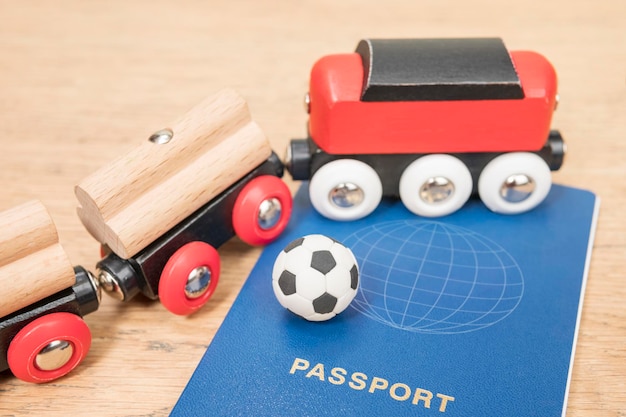 Bola de futebol em miniatura em um passaporte biométrico em um trem de brinquedo em uma mesa de madeira