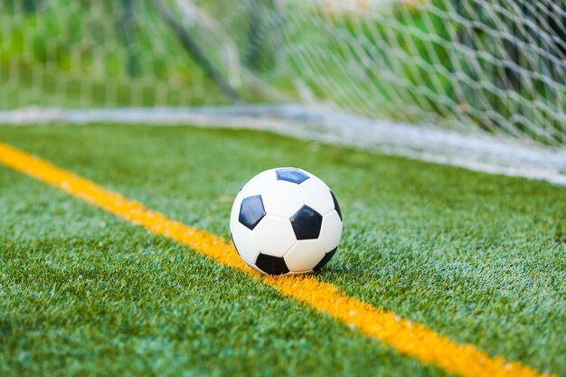 Bola de futebol em um campo artificial de futebol com fundo de rede de gols