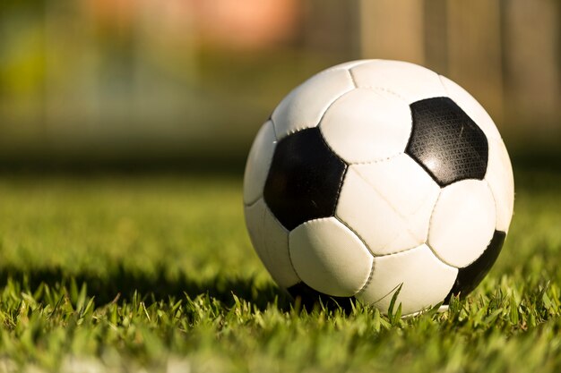 Bola de futebol em um campo de grama, sob o pôr do sol.