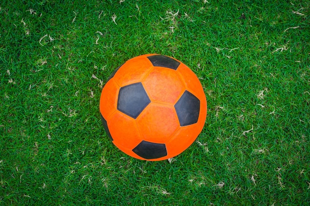 Foto bola de futebol laranja no campo verde