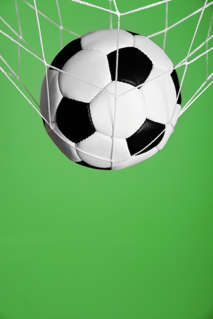 Foto bola de futebol na rede em fundo verde