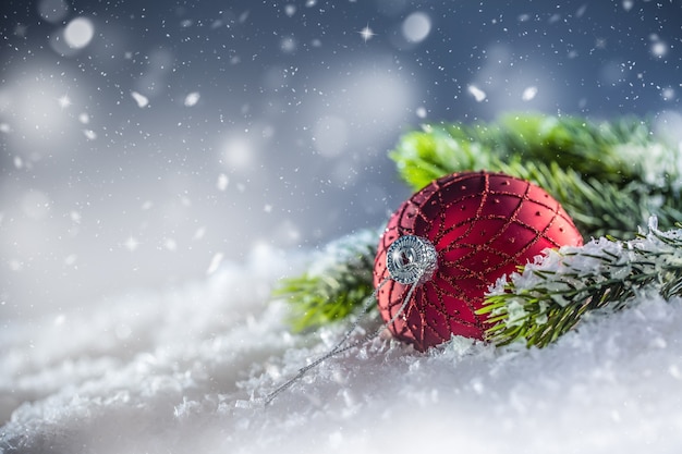 Bola de luxo vermelha de Natal na neve e na atmosfera abstrata de neve.