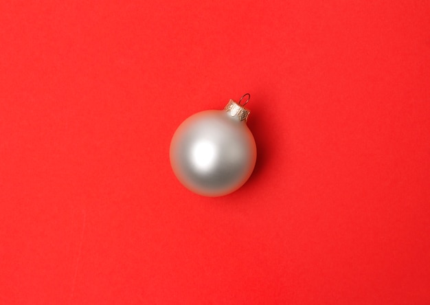 Bola de Natal branco sobre a mesa de papel vermelho.