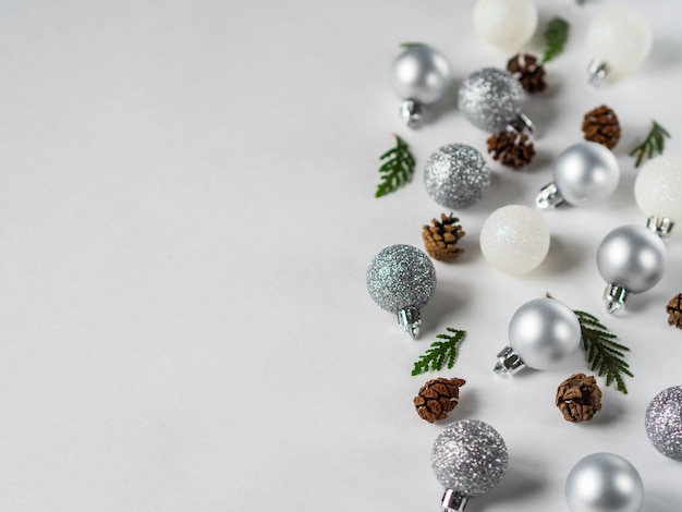 Bola de Natal de prata e gliter branco, cones e galho de árvore de Natal fronteira plana leigos. Copie o espaço