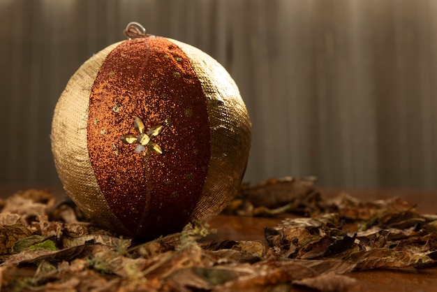 Bola de Natal dourada e marrom entre folhas secas