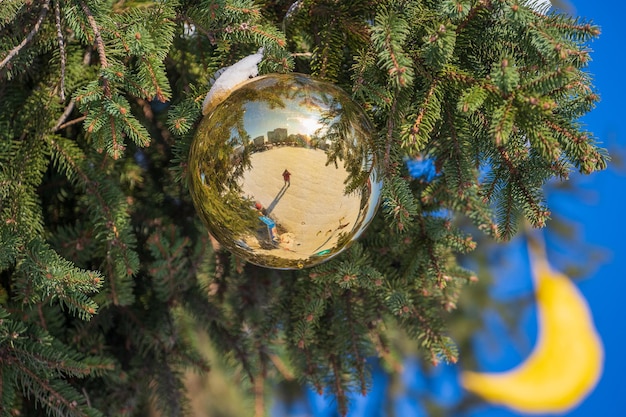 Bola de Natal dourada em um galho de pinheiro verde no fundo do céu azul