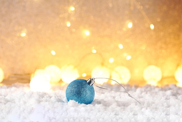 Bola de natal na neve e luzes de natal no fundo desfocado.