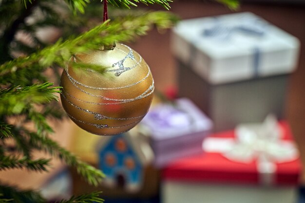 Bola de Natal no galho da árvore de Natal com caixas de presente no fundo desfocado