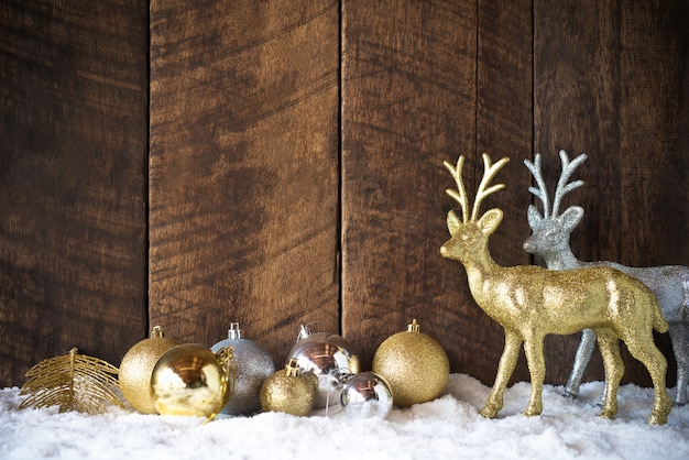 Bola de natal ouro prata e decoração de renas com fundo de madeira