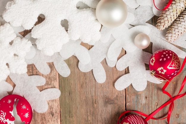 Bola de Natal vermelha e branca e fitas em fundo de madeira perto de floco de neve e pinho