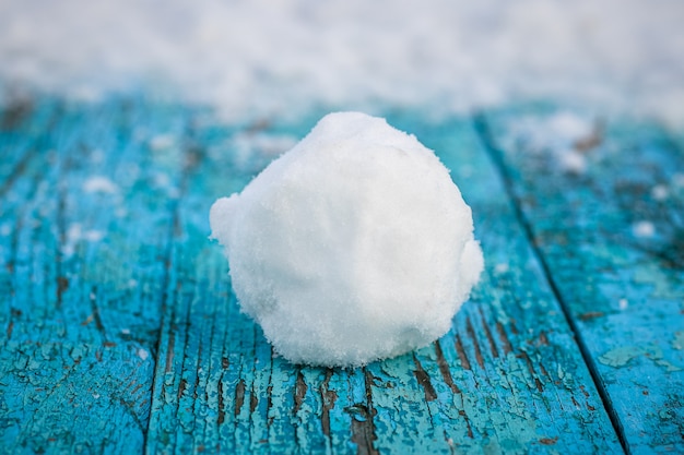 Foto bola de neve repousa sobre um tabuleiro pintado de azul coberto de neve