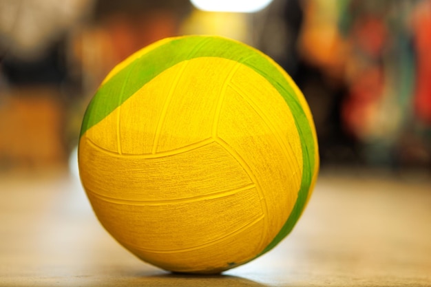 Bola de pelúcia verde-amarelo no chão no ginásio em um fundo multicolorido