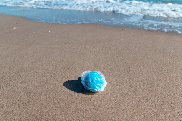 Bola de planeta em um saco de plástico no mar. conceito de poluição ambiental.