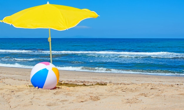 Bola de praia sob um guarda-sol amarelo na costa