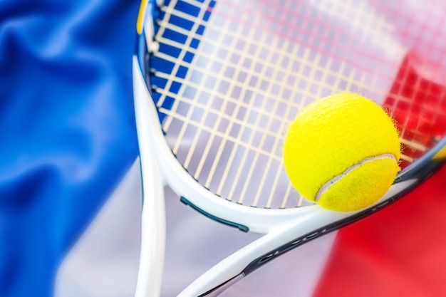 Bola de tênis amarela e raquete de tênis branca em fundo da bandeira francesa