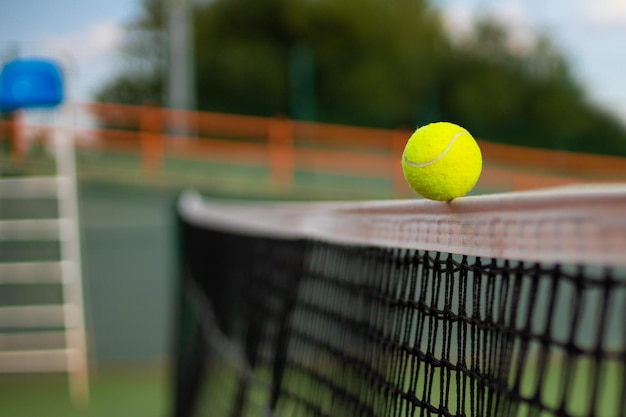 Bola de tênis amarela esverdeada brilhante batendo na rede