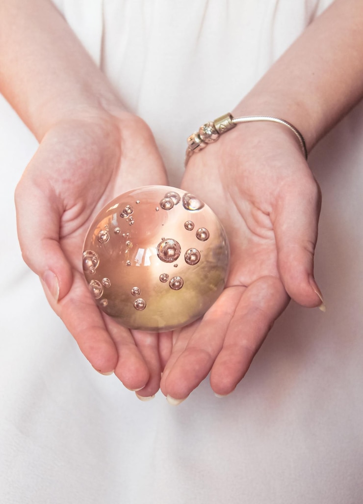 Foto bola de vidro mágica nas mãos de uma menina em um fundo claro
