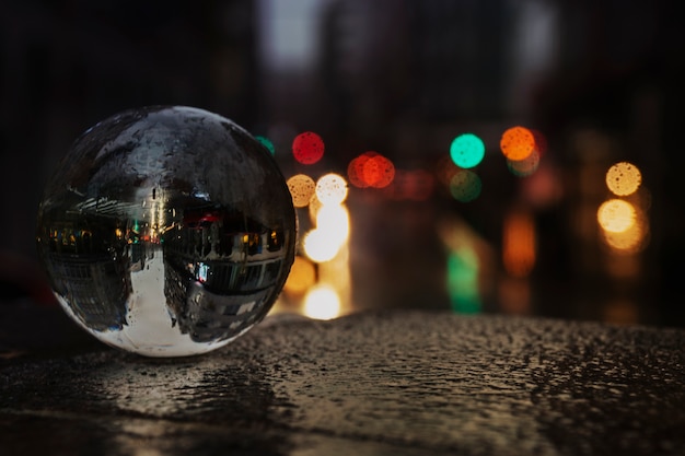 Foto bola de vidro na rua debaixo de chuva com alguns faróis de carro