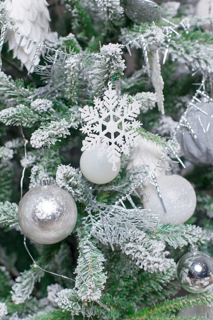 Bola decorativa branca na árvore de Natal em fundo de bokeh de brilho com neve turva.