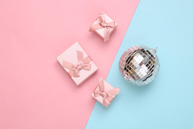 Bola de discoteca y cajas de regalo sobre fondo rosa azul Minimalismo fiesta y concepto de vacaciones