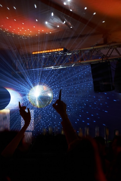 Bola de discoteca en una fiesta gente y multitud con festival de música rave y luces con celebración y emoción Público hombres y mujeres con concierto y alegre con evento de Año Nuevo y entretenimiento